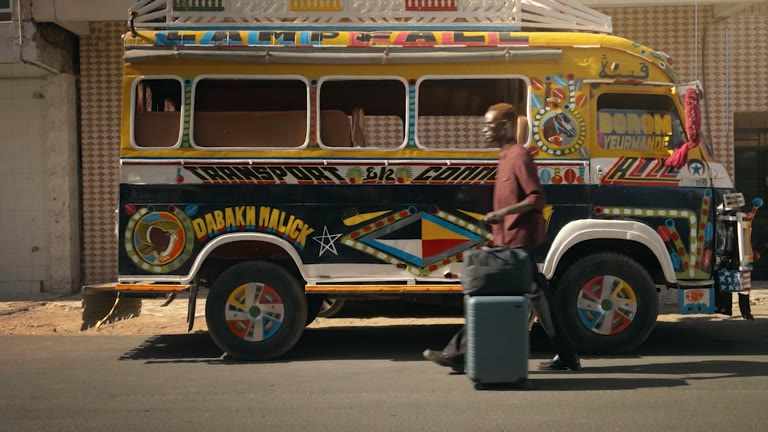 A traveler rolls Away luggage past a painted Dakar bus